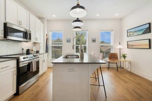 A modern kitchen with white cabinetry, stainless steel appliances, and a central island.