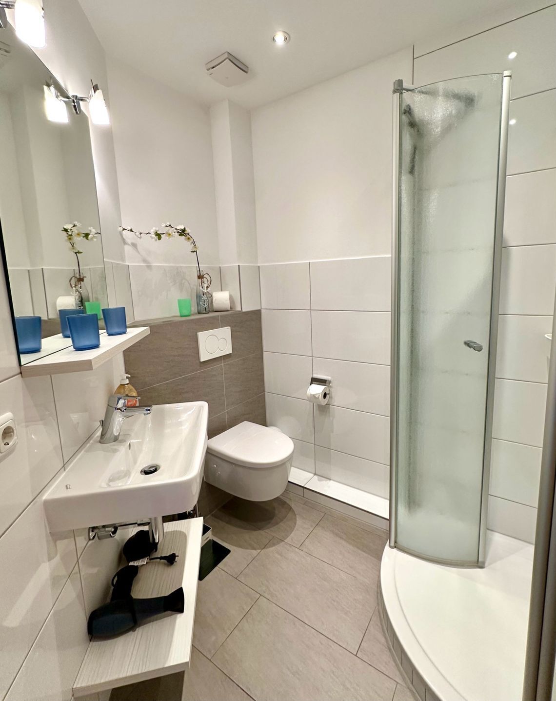 A modern bathroom with a white sink, toilet, and glass shower enclosure.