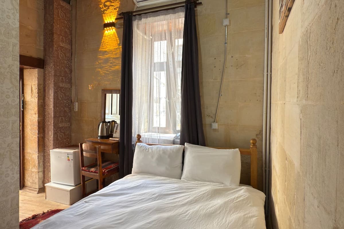 Un dormitorio con techo de madera, cama, escritorio y aire acondicionado.