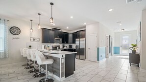 Una cocina moderna con armarios oscuros, electrodomésticos de acero inoxidable y una isla central con taburetes de bar.
