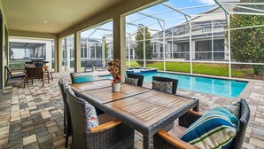 Un patio techado con piscina, mobiliario exterior y una estructura tipo invernadero.
