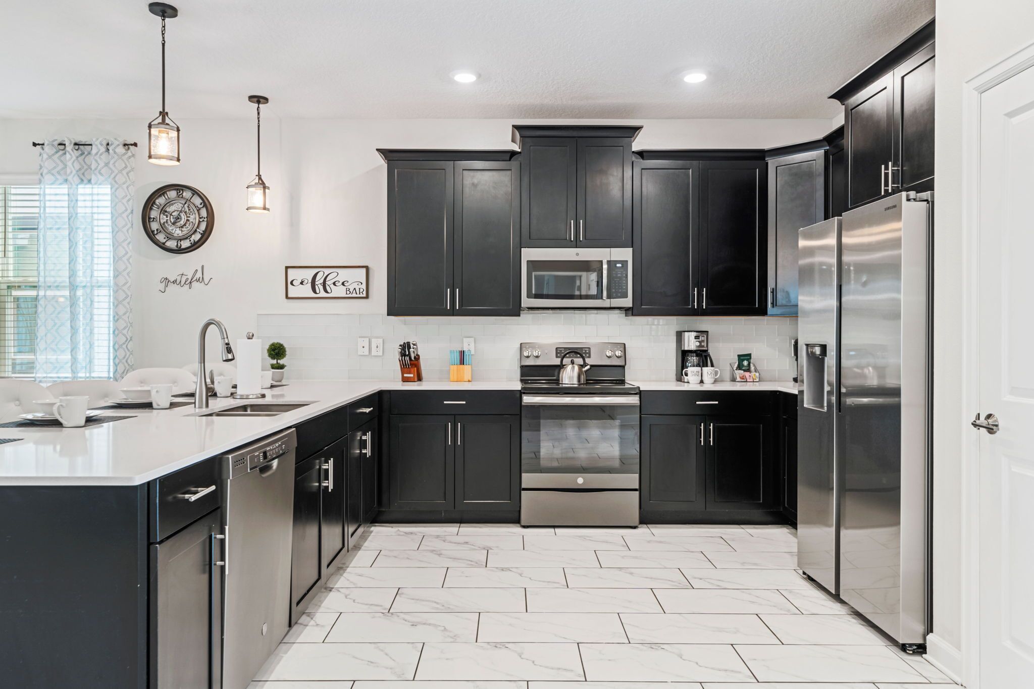 A modern kitchen with dark cabinets, stainless steel appliances, and a white countertop.