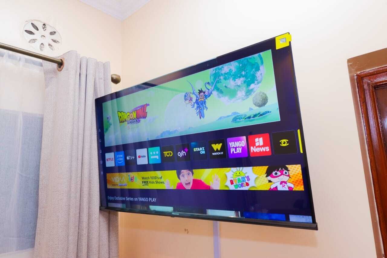 A flat-screen TV mounted on a wall displaying a streaming service interface with various app icons.