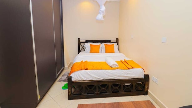 A bedroom with a bed, a wardrobe, and a hanging light fixture. - Machakos Gateaway  (Machakos)