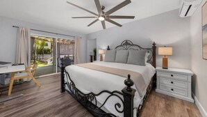 Ein Schlafzimmer mit einem Bett, einem Schreibtisch, einem Stuhl, einem Deckenventilator, einem Nachttisch und einer Klimaanlage.