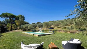 A poolside area with two wicker chairs, a small table with drinks, and a covered boat.