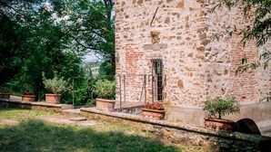 A rustic stone building with a small window and a metal railing.