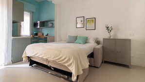 Une chambre comprenant un lit, un bureau, un coin cuisine et un placard.