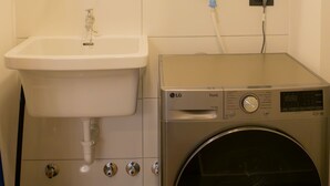 Ein kleiner Hauswirtschaftsraum mit Waschmaschine, Spüle und Warmwasserbereiter.