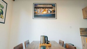 Un comedor con mesa de madera, sillas y una cafetera.