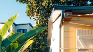 Una terraza de madera que conduce a un pequeño edificio con ventana y puerta.