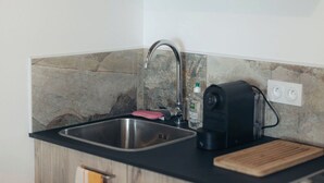 Eine kleine Küche mit integriertem Mikrowellenherd, Spüle und Kaffeemaschine.