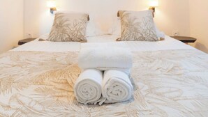Ein Schlafzimmer mit einem großen Bett, zwei Nachttischen, einer Wand-Klimaanlage und einem gerahmten Bild von einem Wasserrad.