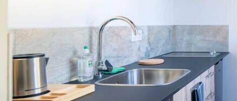 Eine moderne Küche mit schwarzem Arbeitsplatz, Spüle aus Edelstahl, Holzschränken und einer Mikrowelle.