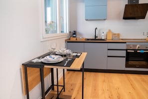 A modern kitchen with a wooden table set for dining, a built-in oven, and a window providing natural light.
