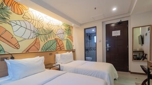 A hotel room with two beds, a large floral mural, a wooden headboard, a door with a sign, and a mirror on the wall. - Maharlika City Inn  (Bacolod)