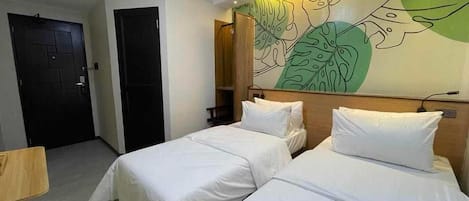 A hotel room with two beds, a wooden headboard, and a wall mural.
