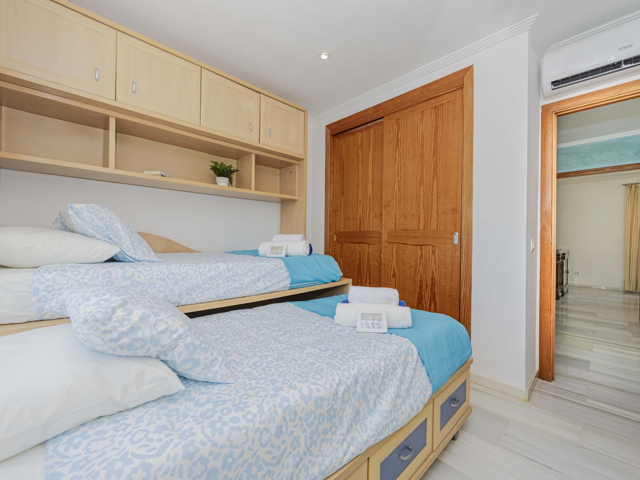 Een slaapkamer met een bed, een houten garderobe en een badkamer zichtbaar door een glazen deur.