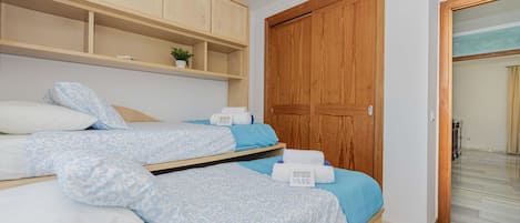 Een slaapkamer met een bed, een houten garderobe en een badkamer zichtbaar door een glazen deur.