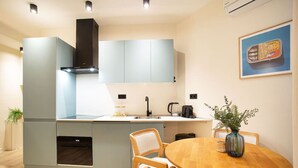 A modern kitchen with grey cabinets, a built-in oven, and a round wooden dining table with chairs. - Modern apartment near Scheveningen beach (Den Haag)