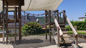 Une aire de jeux dotée de structures en bois, notamment un filet d’escalade et un toboggan.