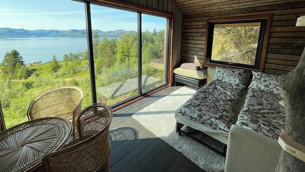 A room with a large sliding glass door, wooden ceiling, and a bed with floral bedding.