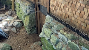 A rustic wooden building with a wooden door and a stone foundation.