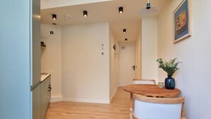 Una cocina moderna con armarios de madera, un comedor con mesa y sillas de madera, e iluminación empotrada en el techo.