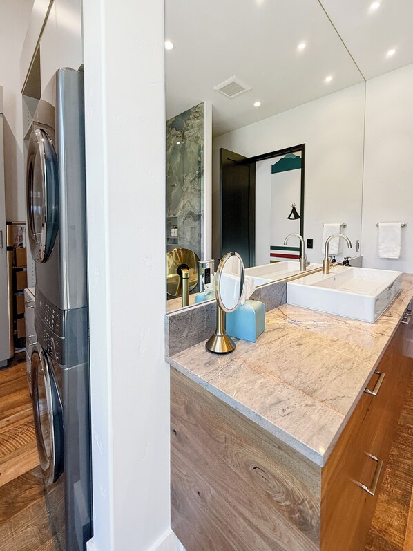 A modern bathroom with a large mirror, dual sinks, and a built-in washing machine. - Halfmoon Camp | Luxury Near Glacier (West Glacier)