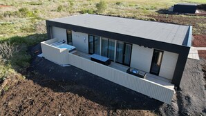A modern, single-story building with a flat roof, large windows, and a small deck area.