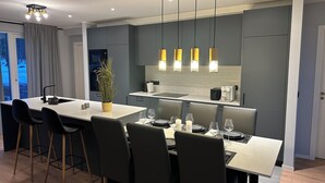 A modern kitchen with a central island, bar stools, and pendant lighting.