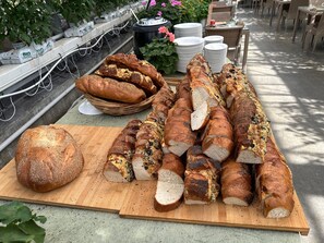A variety of breads on a wooden cutting board, with a wicker basket and stacked plates in the background. - Perfect Icelandic getaway with hot tub under the stars! (Grímsnes- og Grafningshreppur)