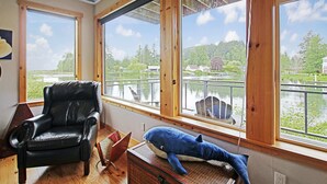 Une pièce avec une grande fenêtre, un fauteuil en cuir et un jouet en peluche représentant un requin bleu.