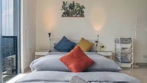 Une chambre moderne avec un grand lit, un ventilateur de plafond et une vue sur l’extérieur.
