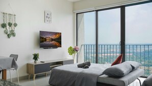 Une chambre moderne avec un grand lit, une télévision, une plante et un balcon offrant une vue sur la ville.