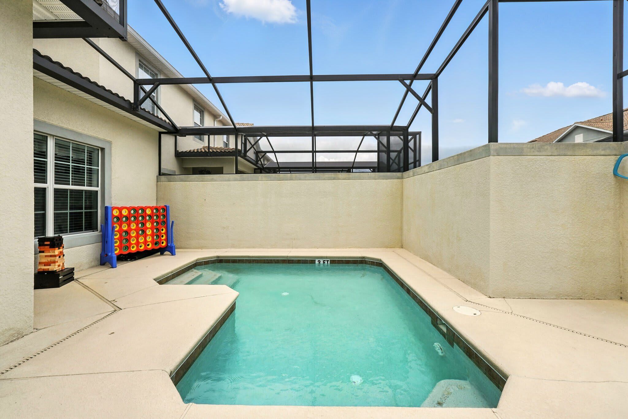 A swimming pool with a glass ceiling, a small deck area, and a colorful game table.