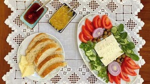 A table with a white lace tablecloth, a plate of sliced bread with butter, a plate of vegetables and cheese, and two small bowls of condiments. - Bed&Breakfast 2 double rooms/4 persons by the sea (Kryevidh)