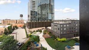 A modern building with a glass facade, a courtyard with seating, and a water tower in the background. - 3BR Apartment Near Clybourn Corridor & Old Town (Chicago)
