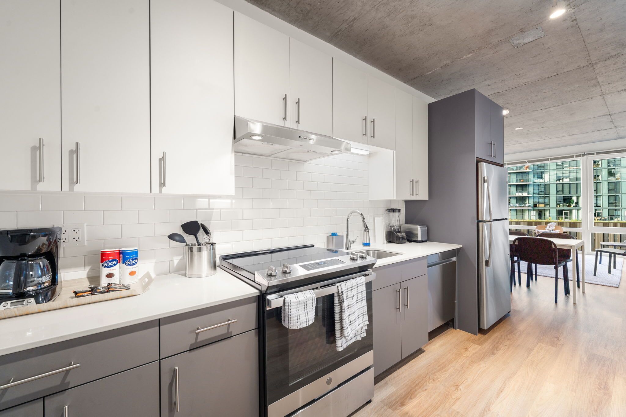 A modern kitchen with white cabinets, stainless steel appliances, and a visible coffee maker.