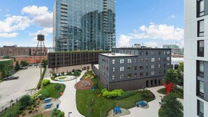 En modern byggnadskomplex med en fasad av glas, en innergård med grönska och en lekplats.