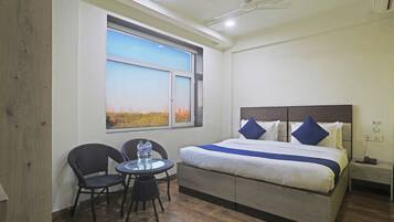 Une chambre d’hôtel avec un lit, une table et des chaises, une fenêtre donnant sur un paysage agréable et un ventilateur de plafond.