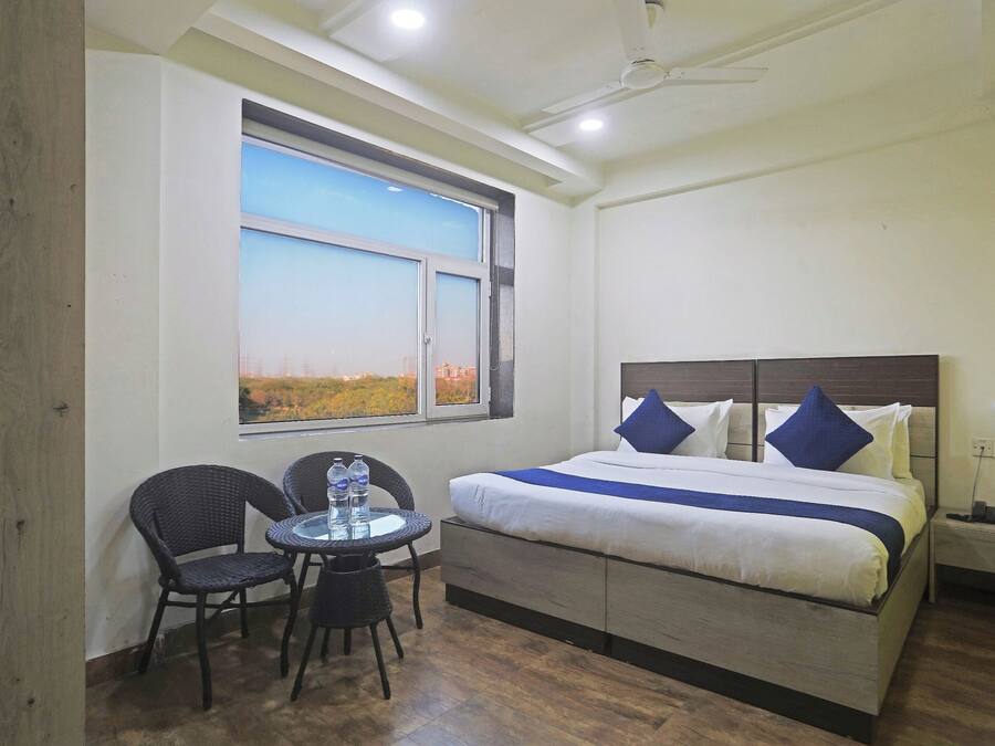 Une chambre d’hôtel avec un lit, une table et des chaises, une fenêtre donnant sur un paysage agréable et un ventilateur de plafond.