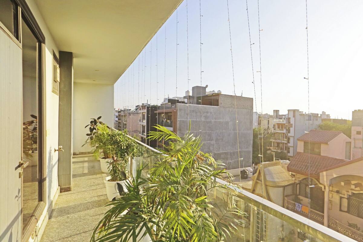 Un balcón con plantas en macetas, vistas despejadas del paisaje urbano y un edificio de techo plano.