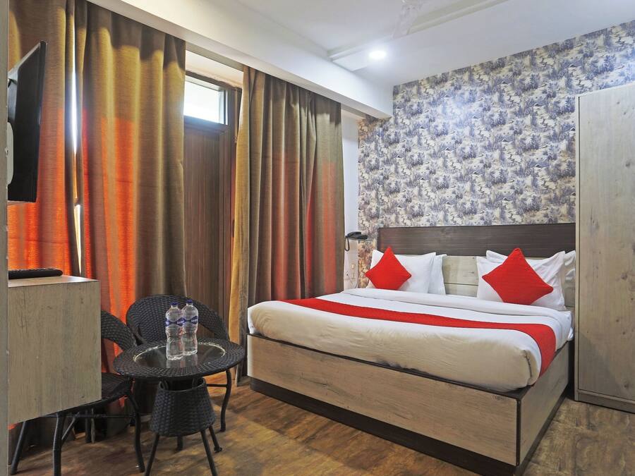 A hotel room with a bed, a desk, a chair, and a wardrobe.