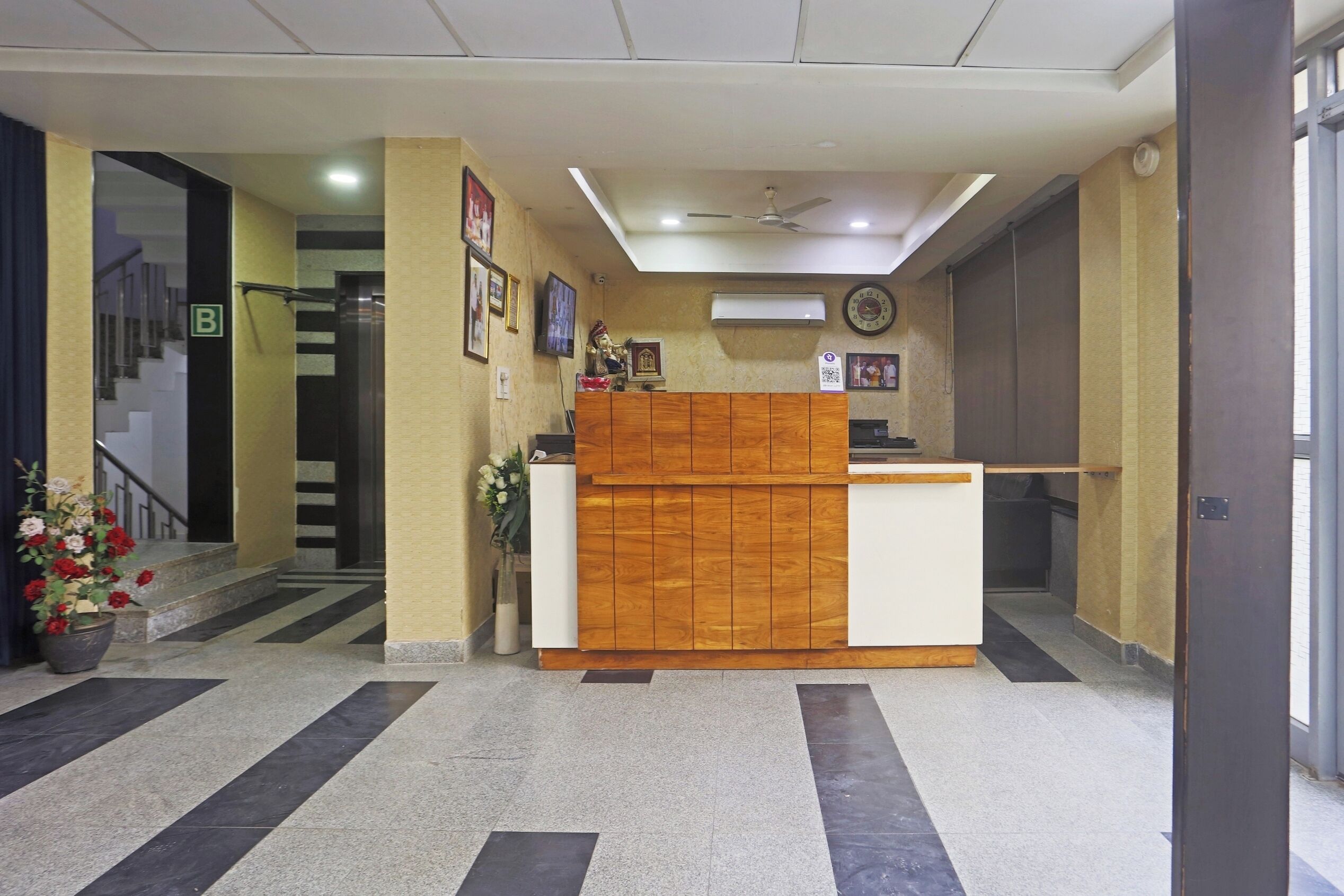 A reception area with a wooden reception desk, a staircase leading to an upper floor, and a wall-mounted air conditioning unit.