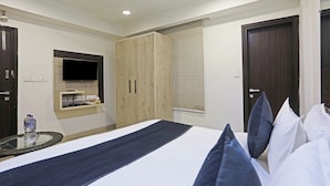 Un dormitorio con cama, armario, televisor y ventilador de techo.