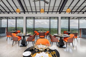 A dining area with tables set for four, large windows offering a view of the landscape, and ceiling fans.