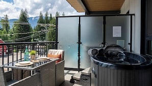Un balcon doté d’un jacuzzi, de meubles en osier et offrant une vue sur les montagnes.