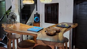 A wooden dining table with chairs, a bookshelf, and two pendant lights.
