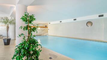 Ein Innenpool mit einer gefliesten Wand, einer Zimmerpflanze und einer Treppe, die zu einer höheren Ebene führt.
